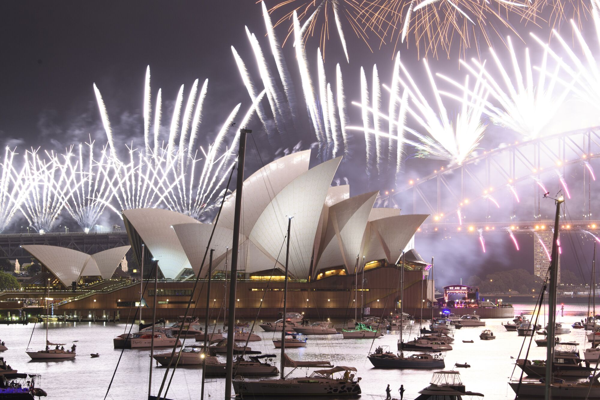 Boats are spaced around Sydney harbor as fireworks explode overhead.