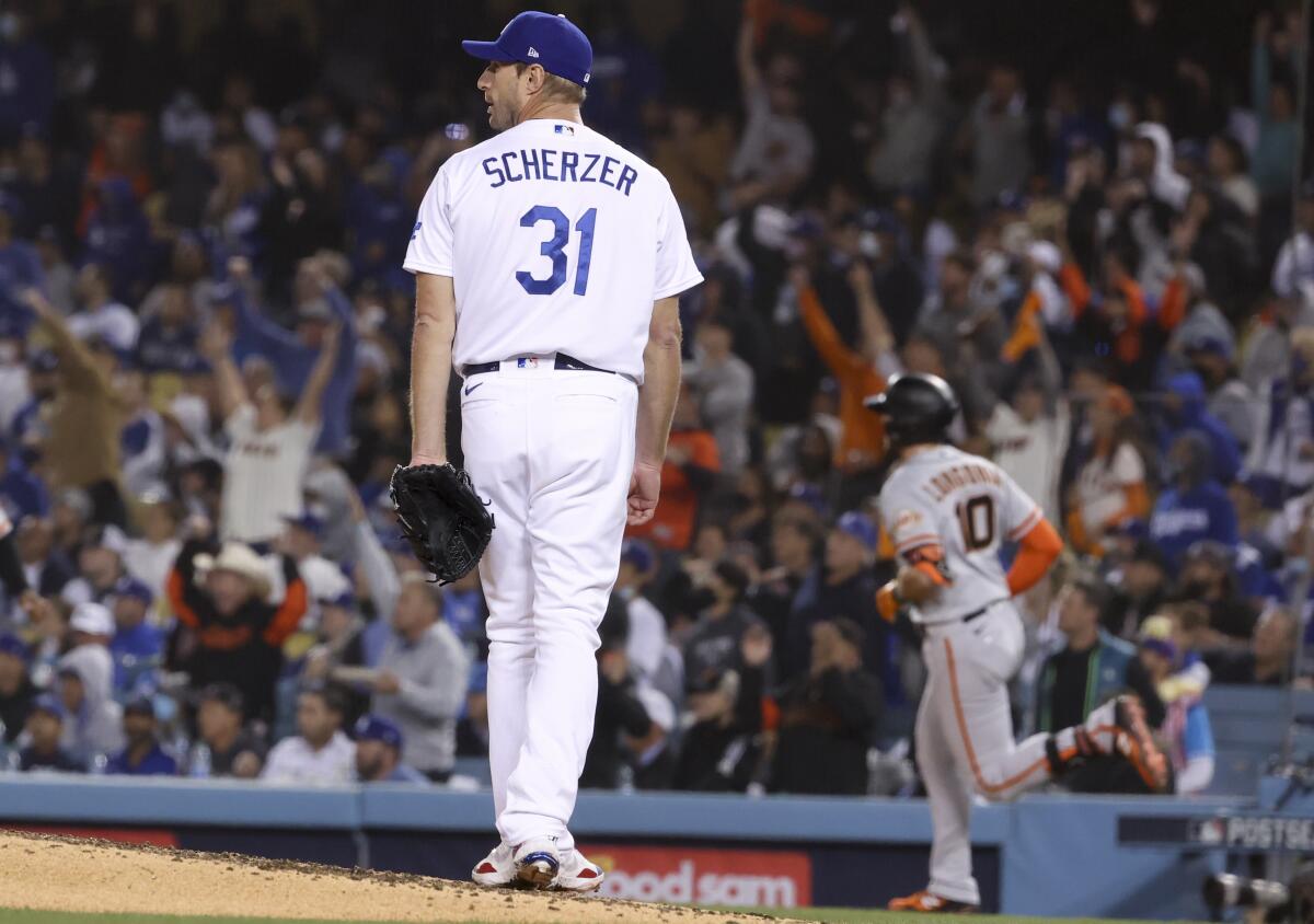 Dodgers starting pitcher Max Scherzer, left, looks back after allowing a solo home run to San Francisco's Evan Longoria.