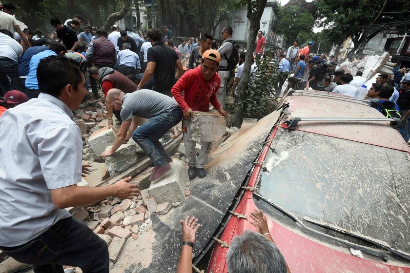 People in Mexico City remove debris after a building collapsed in a powerful earthquake on Tuesday.