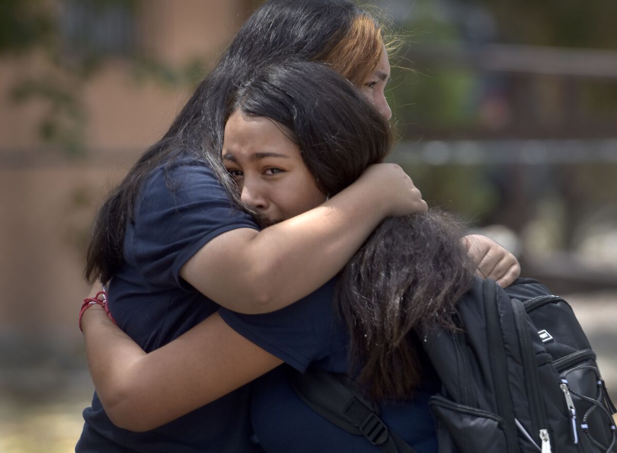 Students embrace after being released from school after a fatal shooting at Washington Middle School in Albuquerque, N.M., Friday, Aug. 13, 2021. New Mexico authorities say one student was killed and another was taken into custody following a shooting at a middle school near downtown Albuquerque during the lunch hour Friday. (Robert Browman/The Albuquerque Journal via AP)
