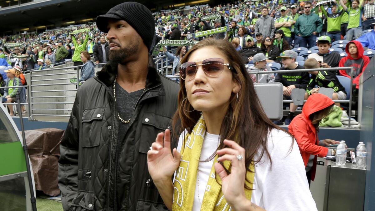 Hope Solo and husband Jerramy Stevens watch an MLS game between the Seattle Sounders and Portland Timbers in Seattle on Aug. 30.