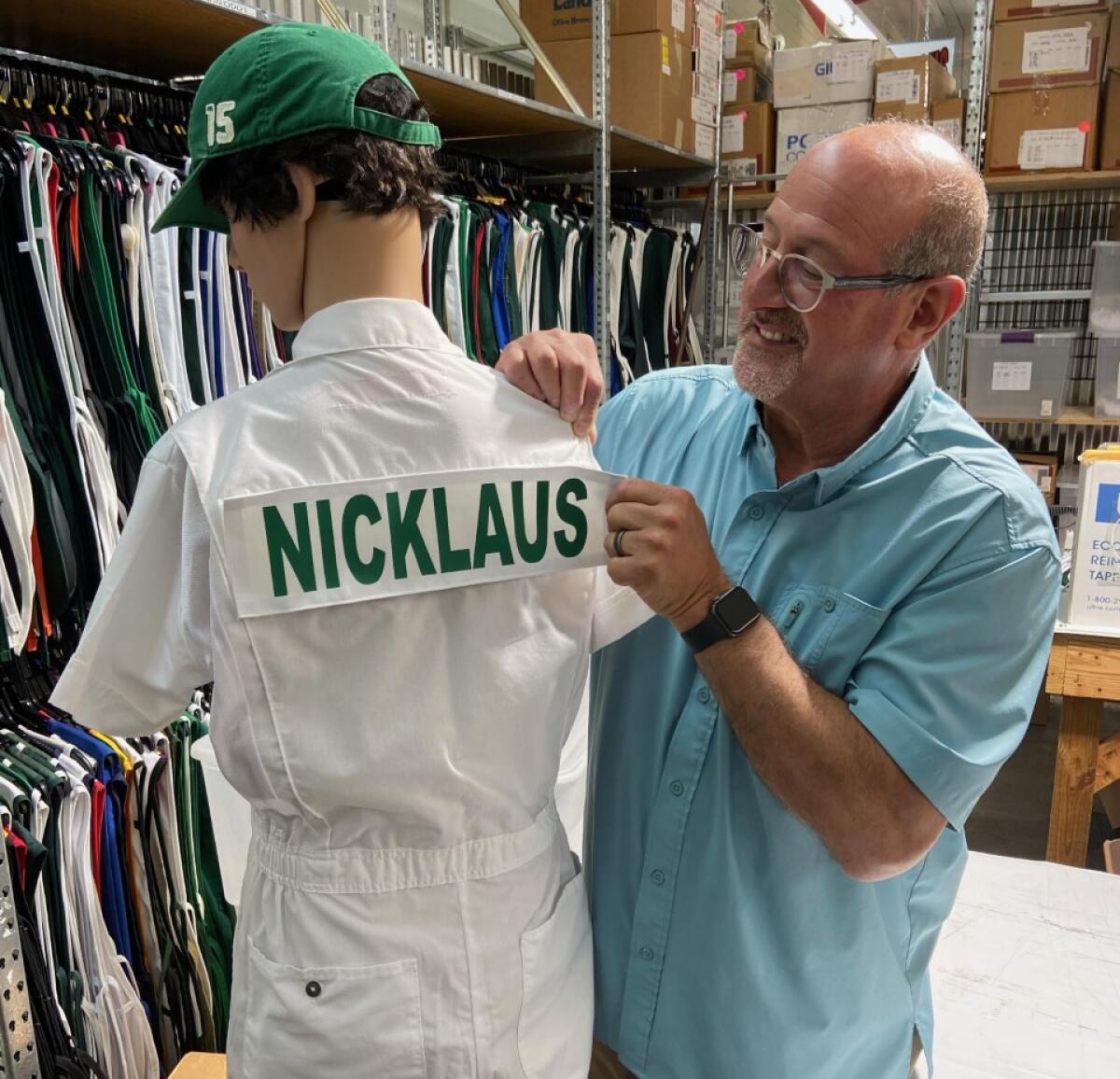 Fred Daitch attaches a name to the back of a caddie coverall, which his family company had supplied for Augusta National.