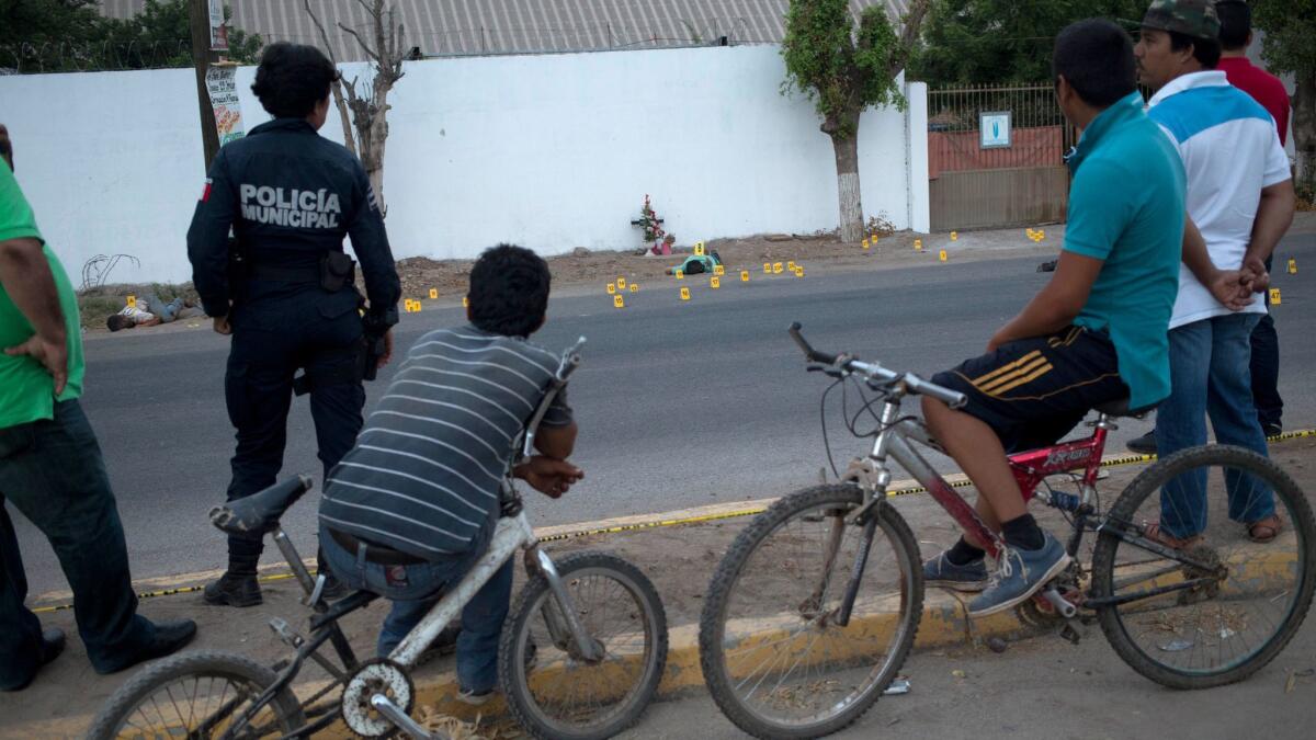 Bystanders look at bodies lying on a road in the town of Navolato, Mexico on June 29.