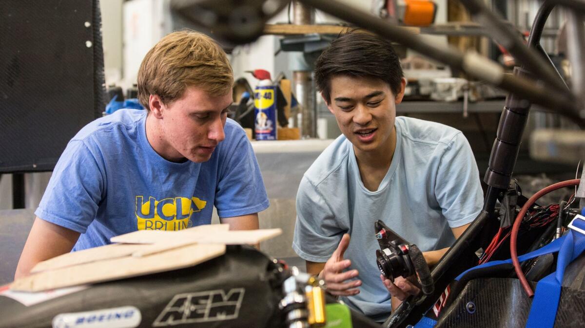 UCLA students Brent Kyono, right, and Luke Allee, left, compare parts for UCLA Formula SAE team car in the Westwood campus workshop.