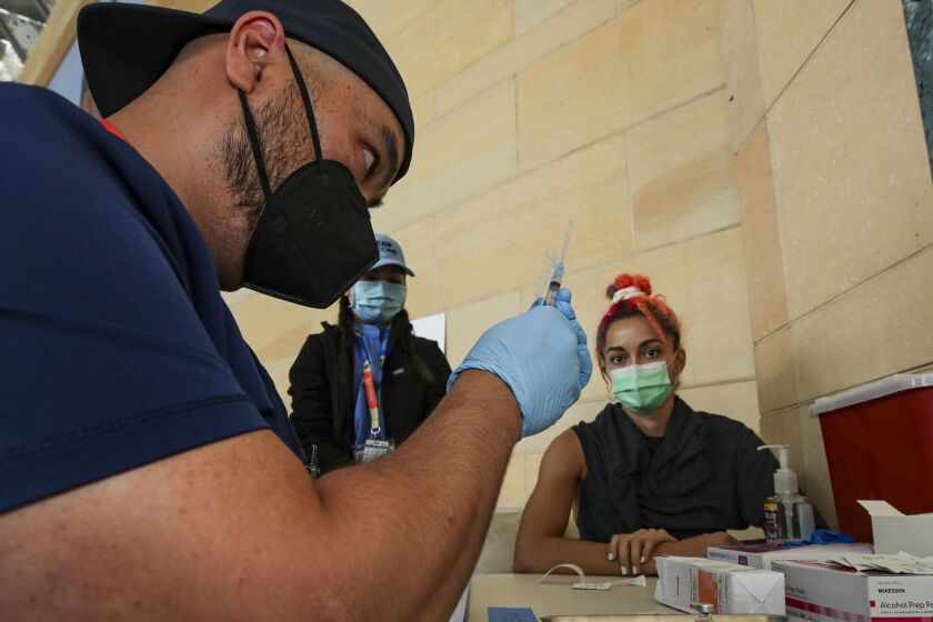Los Angeles, CA - June 08: William Chang, a RN, prepares a Pfizer vaccine to be administered to Sibelle Yuksek, right, at newly inaugurated site at Union Station on Tuesday, June 8, 2021 in Los Angeles, CA. (Irfan Khan / Los Angeles Times)