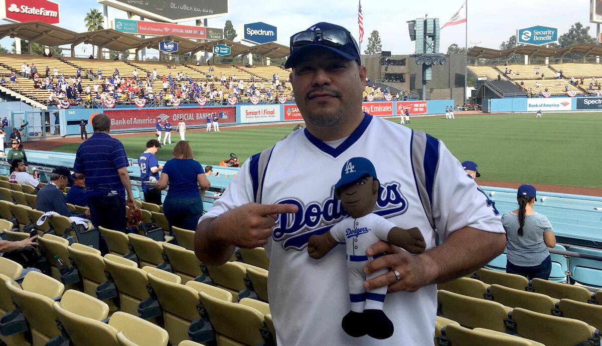 Isaac Tellez travels with his daughter's doll of Yasiel Puig. On Sunday, he was at Dodger Stadium for Game 5 of the World Series.
