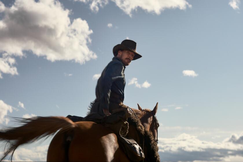 A man in a cowboy hat and chaps rides a horse toward a blue sky studded with white clouds