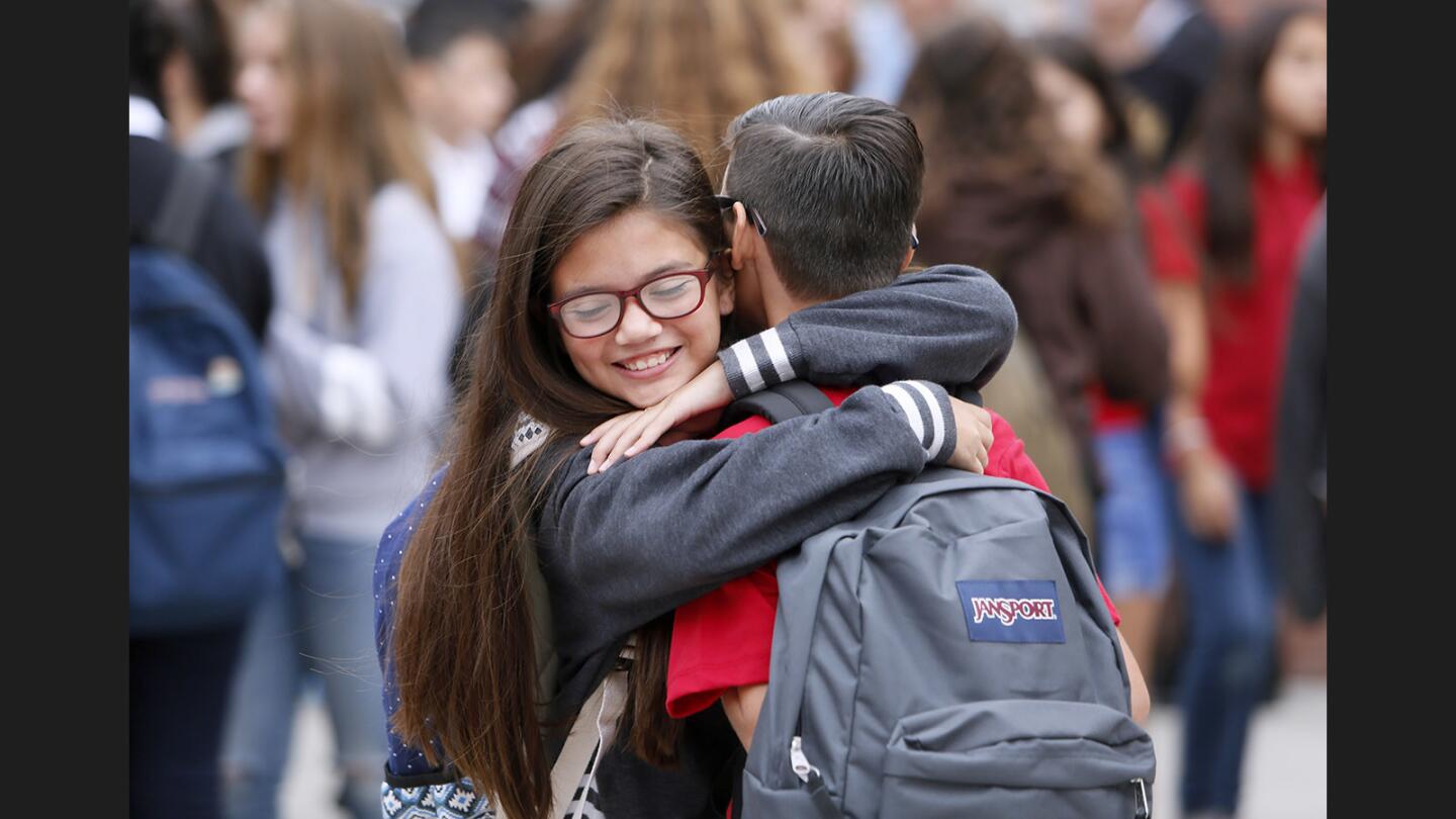 Seventh graders Bella Sanchez, left, and Matthew Ochoa, right, give each other a welcoming hug on the first day of classes at Roosevelt Middle School in Glendale on Wednesday, Aug. 16, 2017.