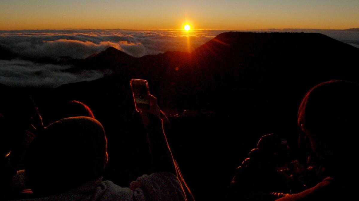People watch as the sun rises in front of the summit of Haleakala volcano in Haleakala National Park on Hawaii's island of Maui on Jan. 22.