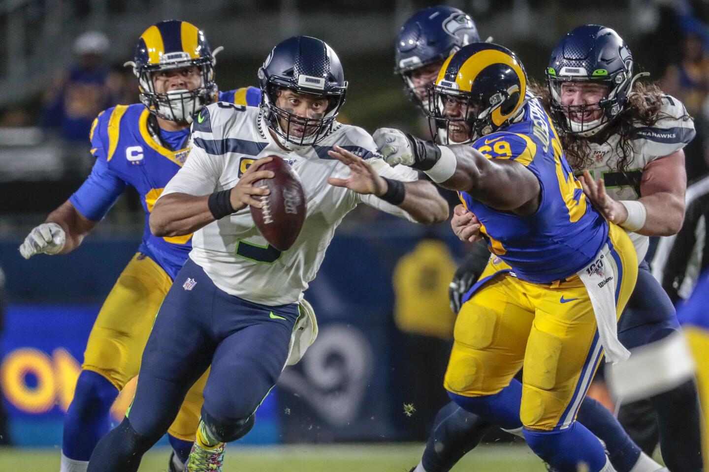Seattle Seahawks quarterback Russell Wilson scrambles past Rams defensive tackle Sebastian Joseph-Day.