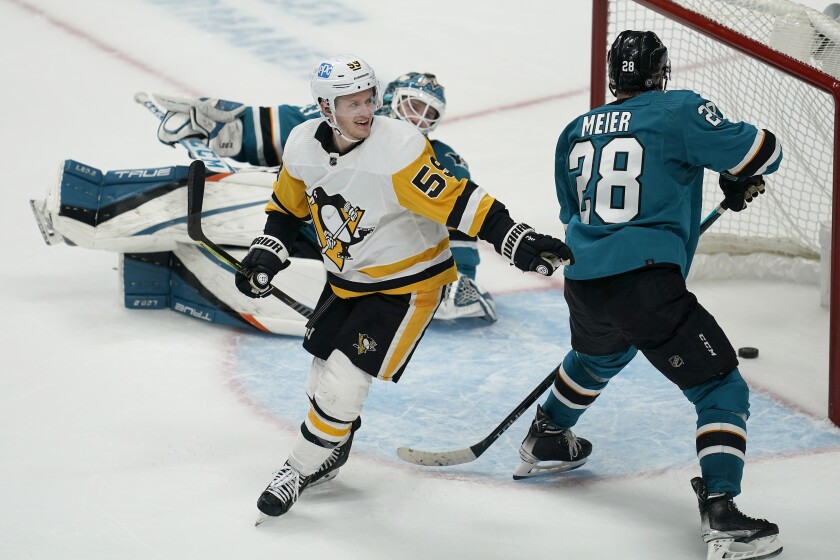 Pittsburgh Penguins left wing Jake Guentzel, left, celebrates after scoring in front of San Jose Sharks goaltender Adin Hill, rear, and right wing Timo Meier (28) during overtime of an NHL hockey game in San Jose, Calif., Saturday, Jan. 15, 2022. The Penguins won 2-1. (AP Photo/Jeff Chiu)