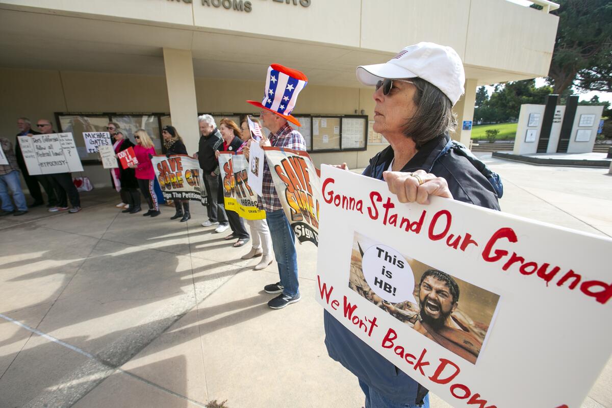 A woman holds a sign during a news conference on Tuesday at Huntington Beach City Hall.
