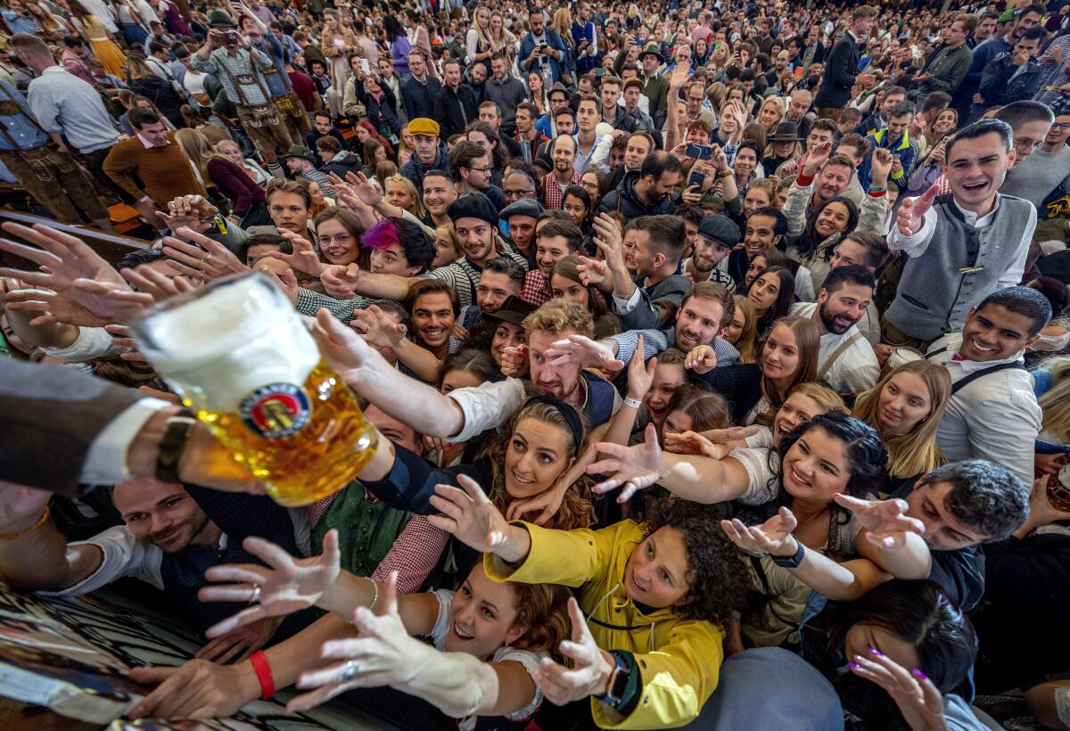 Young people reach out for free beer on the opening day of the 187th Oktoberfest beer festival in Munich, Germany.