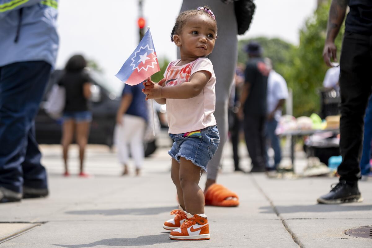 A toddler plays with the Juneteenth flag during a celebration at Black Lives Matter Plaza in Washington.