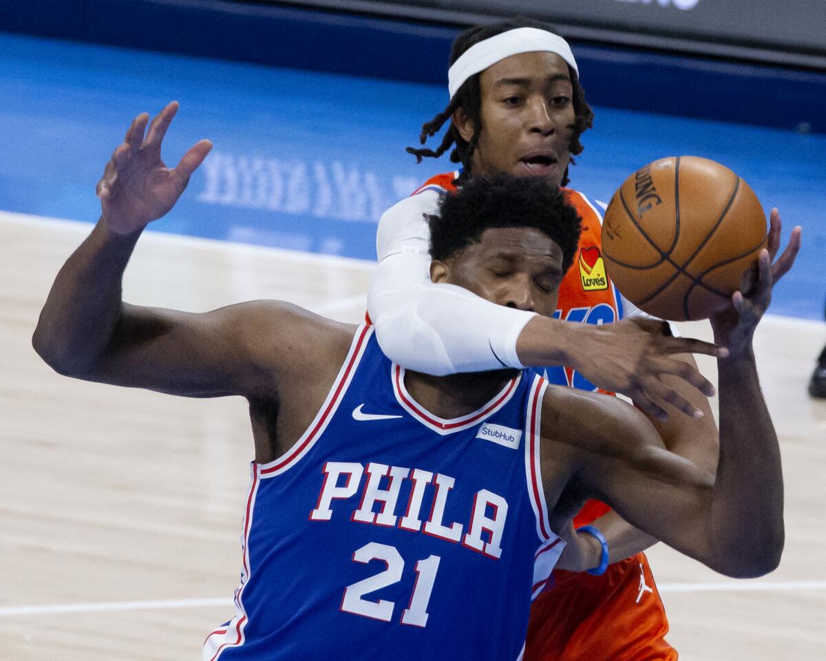 Oklahoma City Thunder center Moses Brown (9) fights for the ball with Philadelphia 76ers center Joel Embiid (21) during the first half of an NBA basketball game, Saturday, April 10, 2021, in Oklahoma City. (AP Photo/Garett Fisbeck)