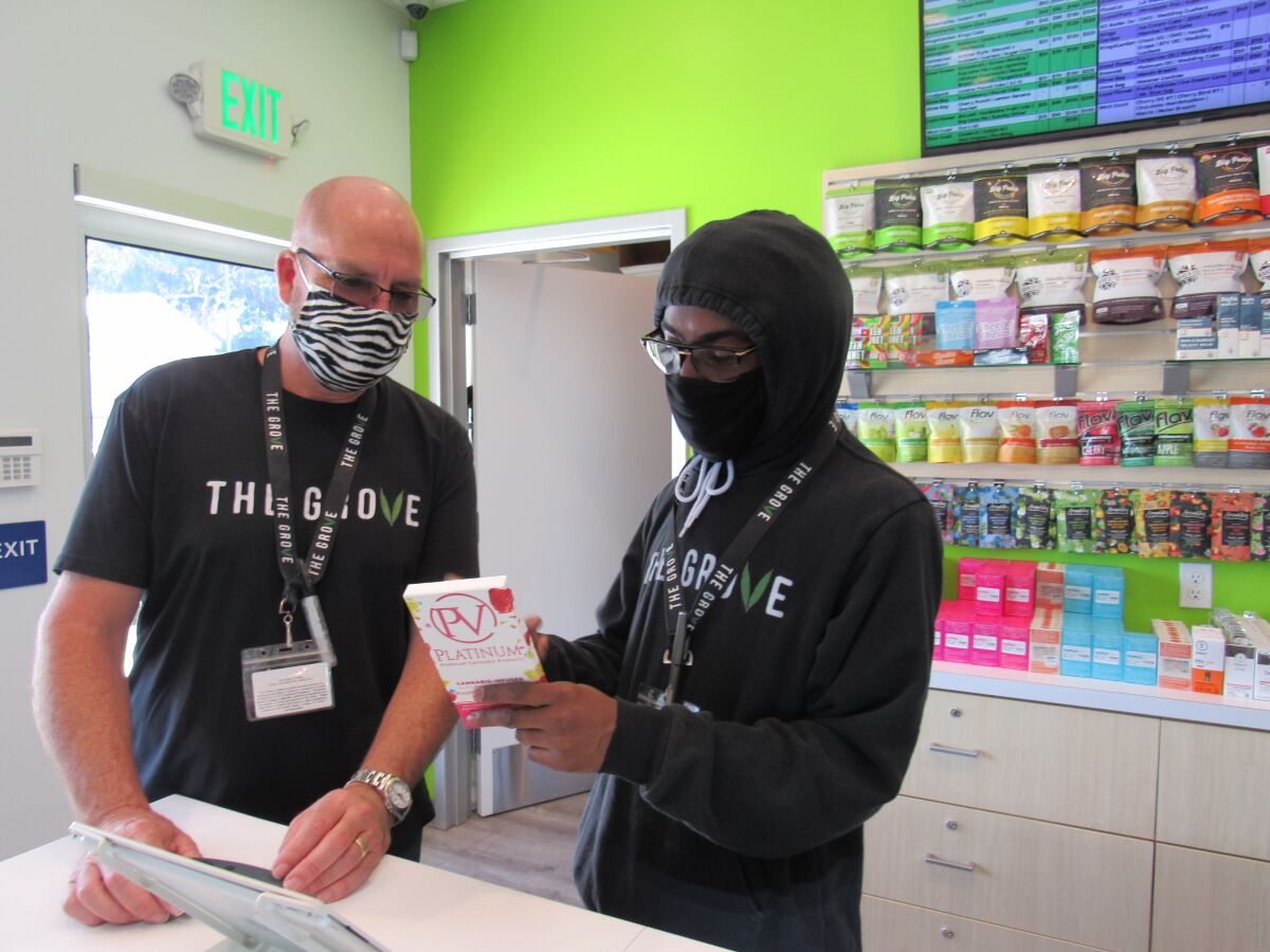 Sean McDermott (left), owner of The Grove cannabis shop in La Mesa, looks over one of the store's products with Larry Fennell, one of his first hires from the summer of 2018. The site on Center Street was the first in East County authorized by California to sell adult-use cannabis products. McDermott said he received confirmation from the state by mail on May 6 and The Grove had its first recreational cannabis product sale on May 7.