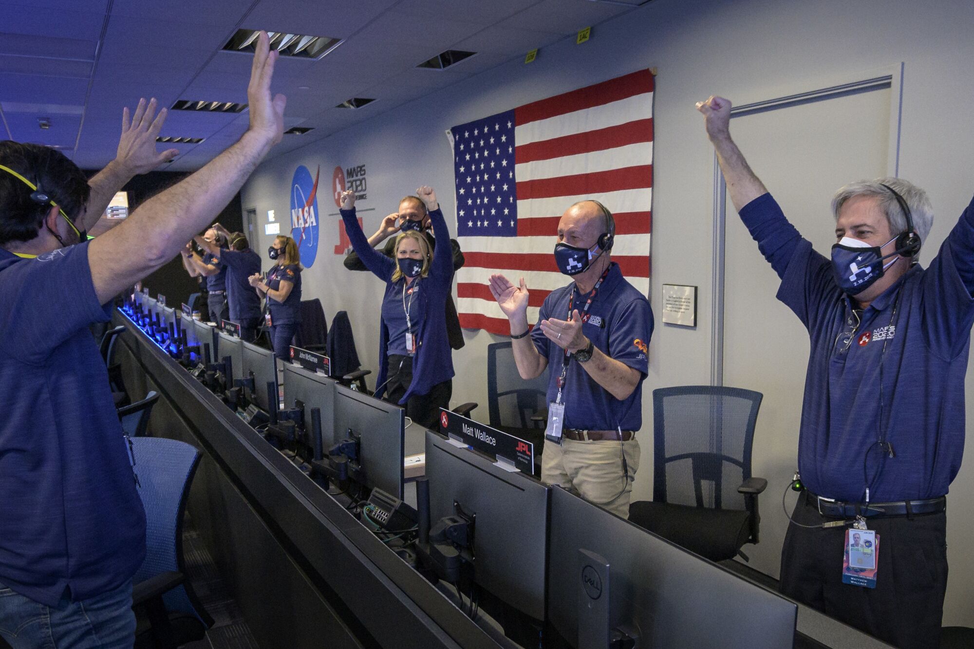 NASA workers raise arms and clap in celebration in mission control