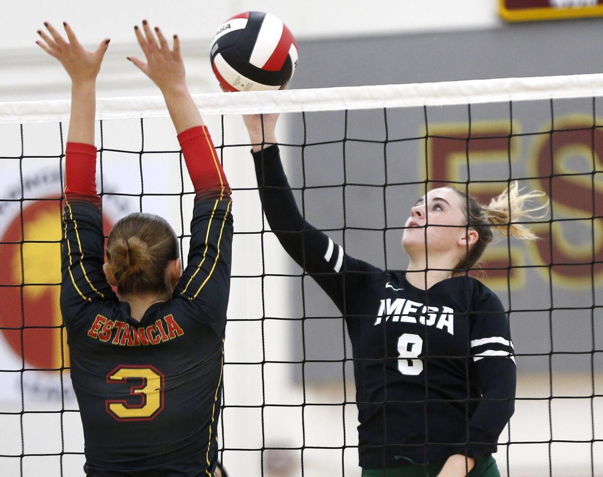 Costa Mesa's Lucca Miller (8) tips a ball over the net past the block of Estancia's Ella Richards on Tuesday.