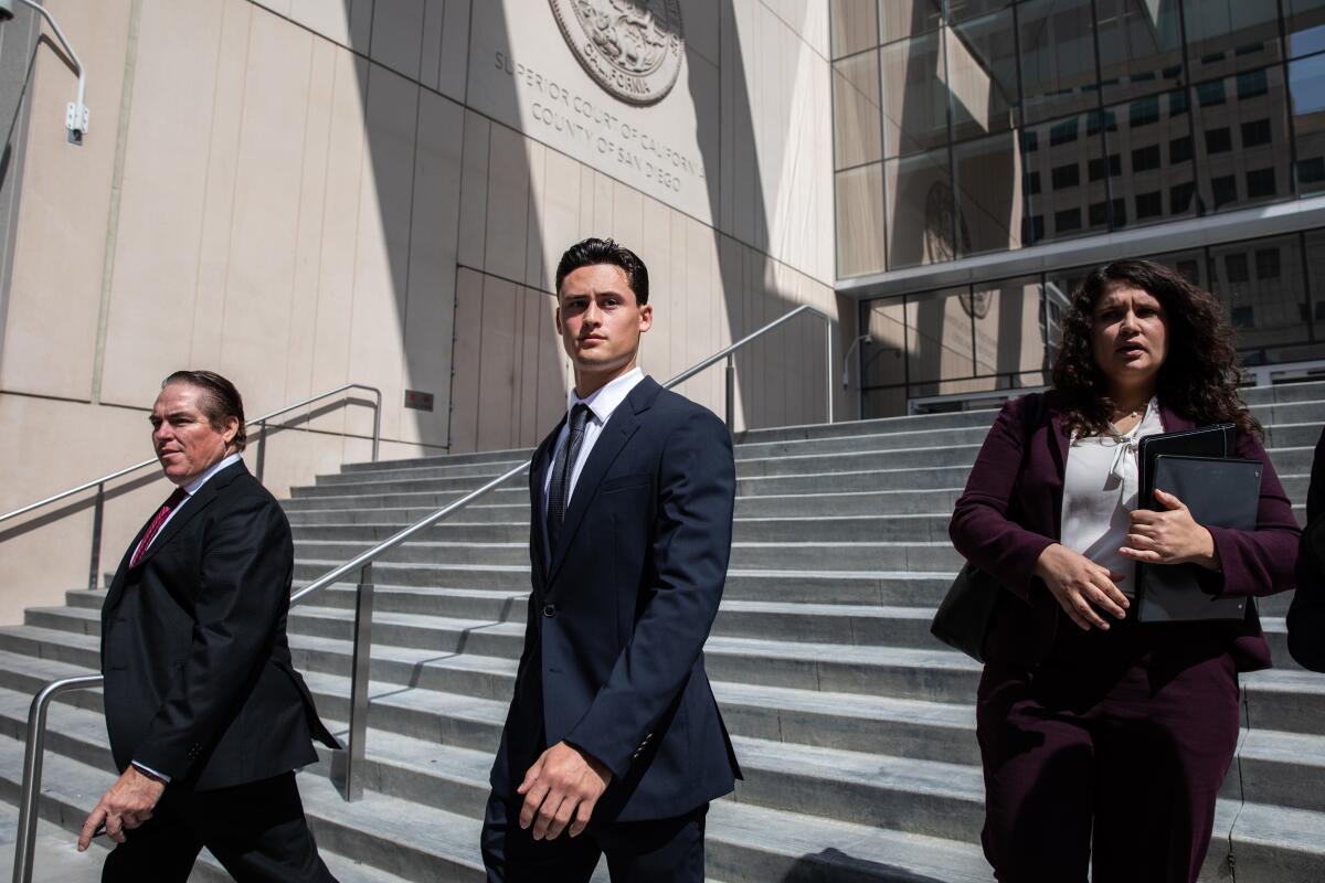 Matt Araiza, center, flanked by two other people wearing suits, leaves a courthouse.
