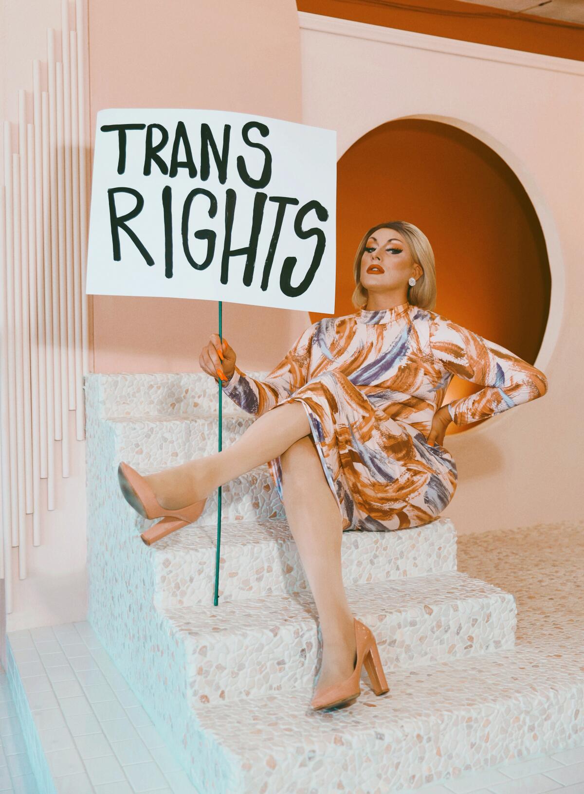 drag queen holds up a sign saying, "Trans rights"