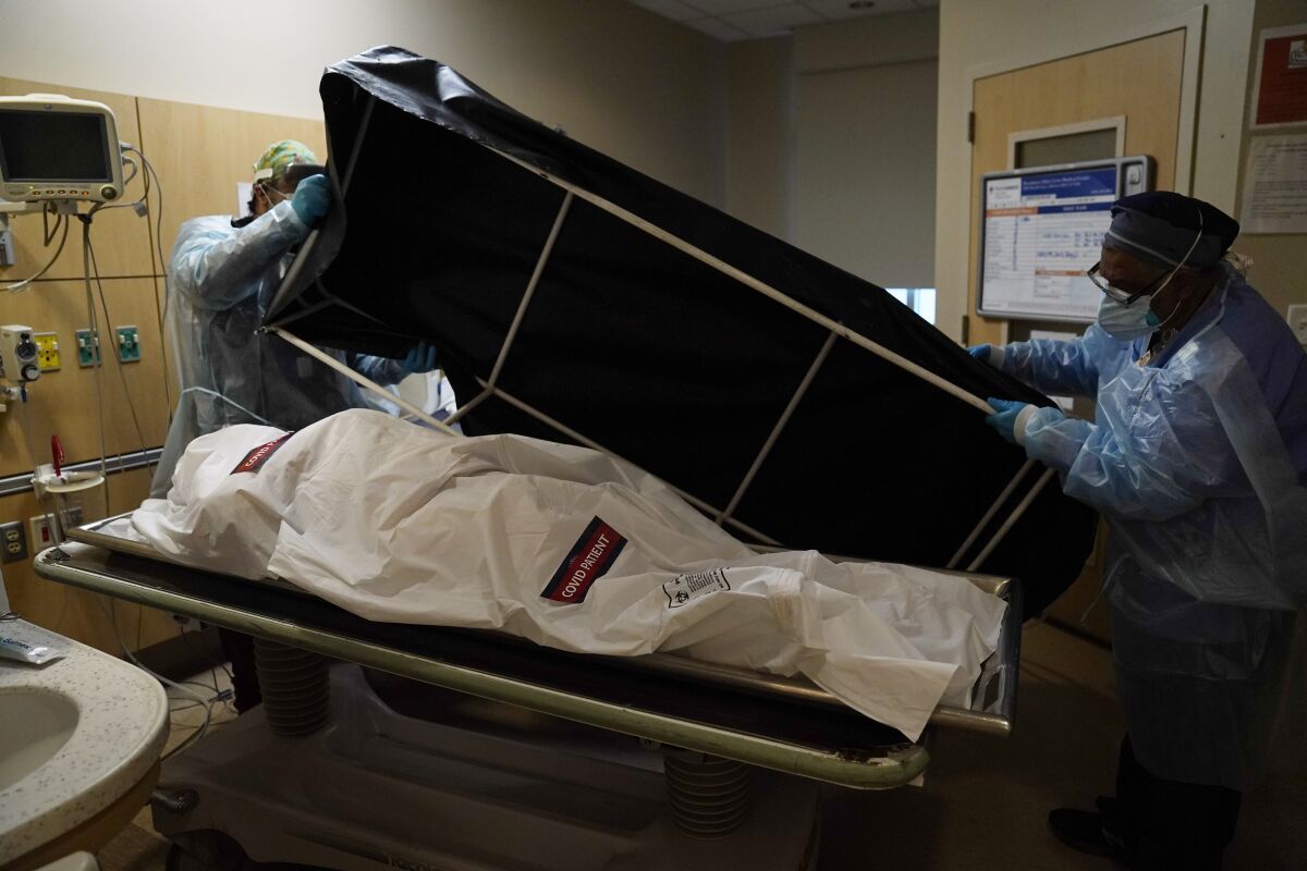 Workers prepare to move the body of a COVID-19 victim to the hospital's morgue.