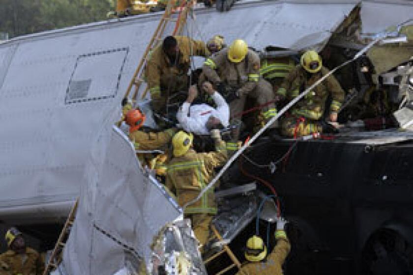 Emergency personnel rescue an injured passenger from a passenger car after the deadly collision between a Metrolink commuter train and a Union Pacific freight train in Chatsworth on Sept. 12, 2008.