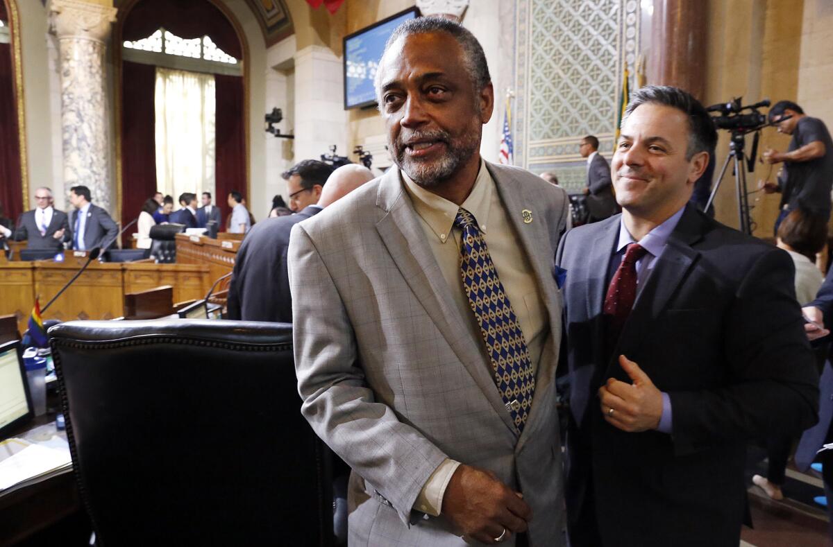 City Councilman Curren D. Price, left, celebrates with fellow Councilman Joe Buscaino, as the council backed a proposed law that Los Angeles workers would be able to earn at least six paid sick days annually.