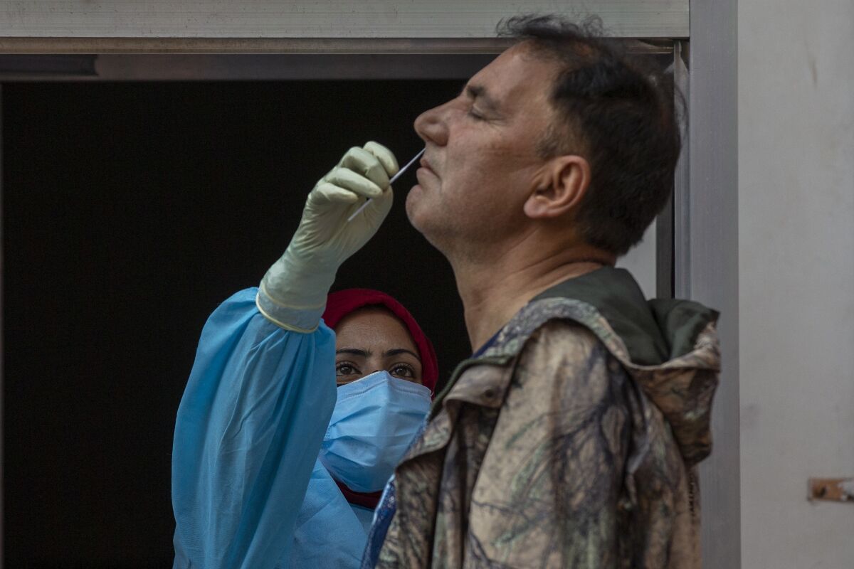 FILE- In this May 11, 2021 file photo, a health worker takes a nasal swab sample of a Kashmiri man to test for COVID-19 in Srinagar, Indian controlled Kashmir. A dip in the number of coronavirus cases in Mumbai is offering a glimmer of hope for India, which is suffering through a surge of infections. (AP Photo/ Dar Yasin, File)