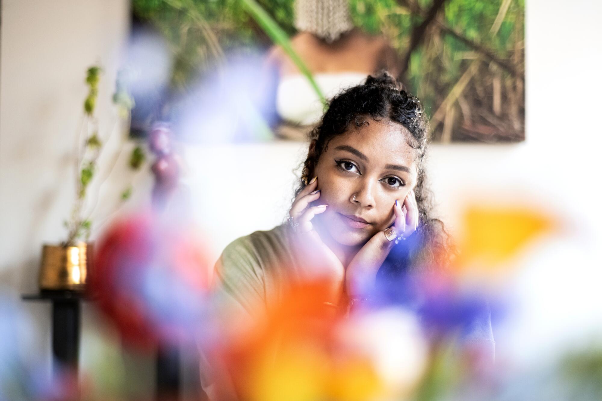 A woman sits at a table with flowers in front of her