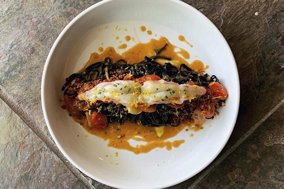 An overhead photo of a bowl of squid ink tagliolini with spot prawns and lobster jus from Laon.