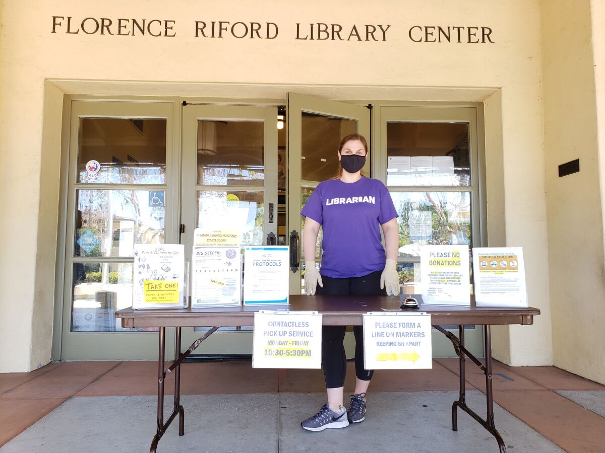 Youth services librarian Dana Sanchez stands at the contactless pickup table at the La Jolla/Riford Library in mid-2020.