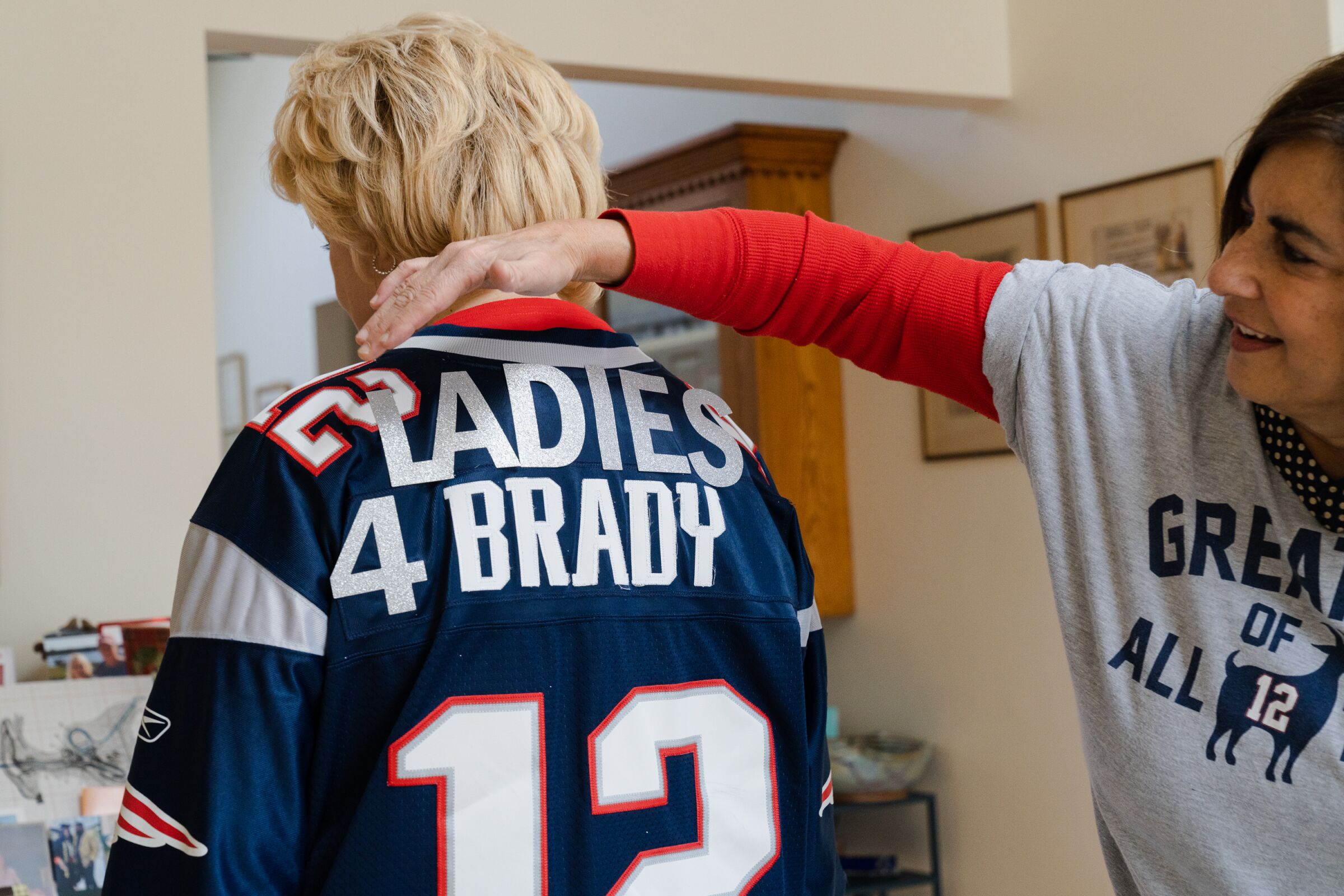 A woman adjusts another woman's jersey with the custom letters 'Ladies 4 Brady'