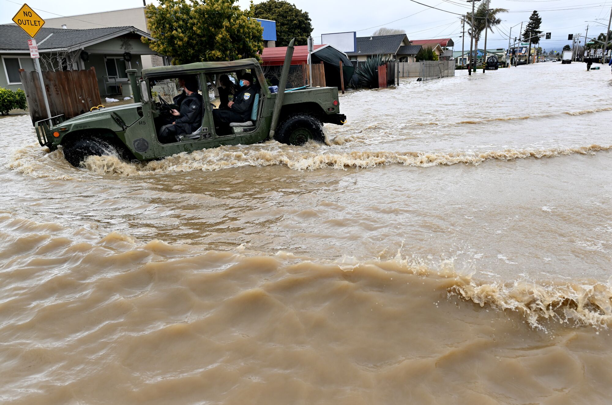 Local police drive a military vehicle along the flooded road from Salinas to Pajaro 