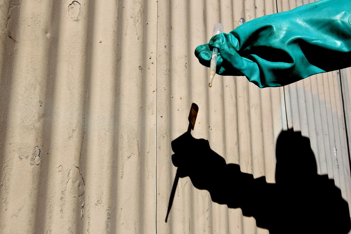 Los Angeles County Fire Department hazardous-materials specialist Don Thompson inspects a sample of a chemical found inside an abandoned container in a South-Central Los Angeles alley.
