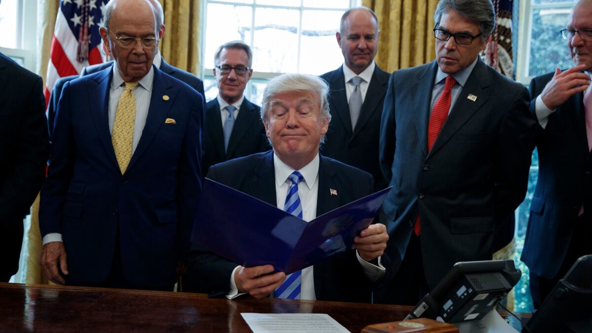 President Trump, flanked by Commerce Secretary Wilbur Ross, left, and Energy Secretary Rick Perry, announces the approval of a permit to build the Keystone XL pipeline, clearing the way for the $8-billion project.