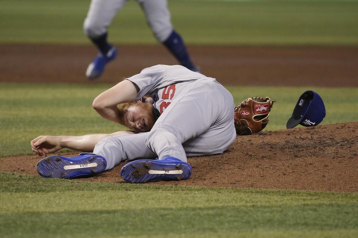 Dodgers pitcher Dustin May rolls on the ground after being hit in the head by a line drive off the bat of the Diamondbacks' Jake Lamb during the fourth inning.