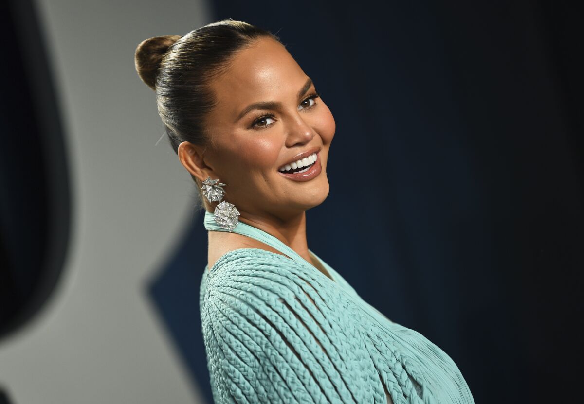 A woman smiling in earrings and a mint green dress