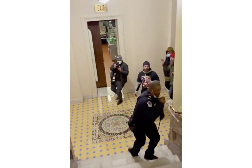 In this image made from video and provided by HuffPost, Capitol Police Officer Eugene Goodman calls for backup as an angry mob gives chase inside the U.S. Capitol in Washington on Jan. 6, 2021. One bright spot in all the chaos and anger from the mob siege at the U.S. Capitol was Goodman confronting a mob and retreating, risking his life to perhaps save the U.S. Senate. (Igor Bobic/HuffPost via AP)