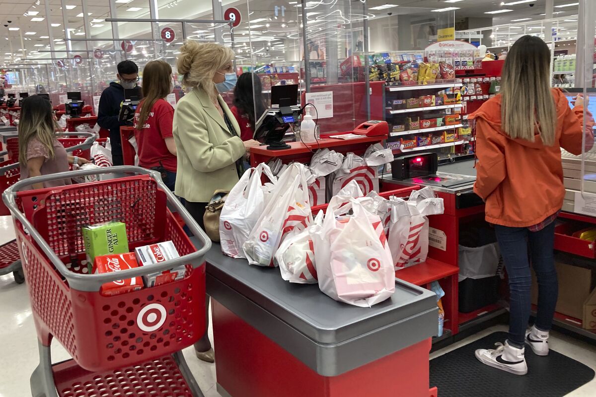 A customer wears a mask as she waits to get a receipt at a register in a Target store.