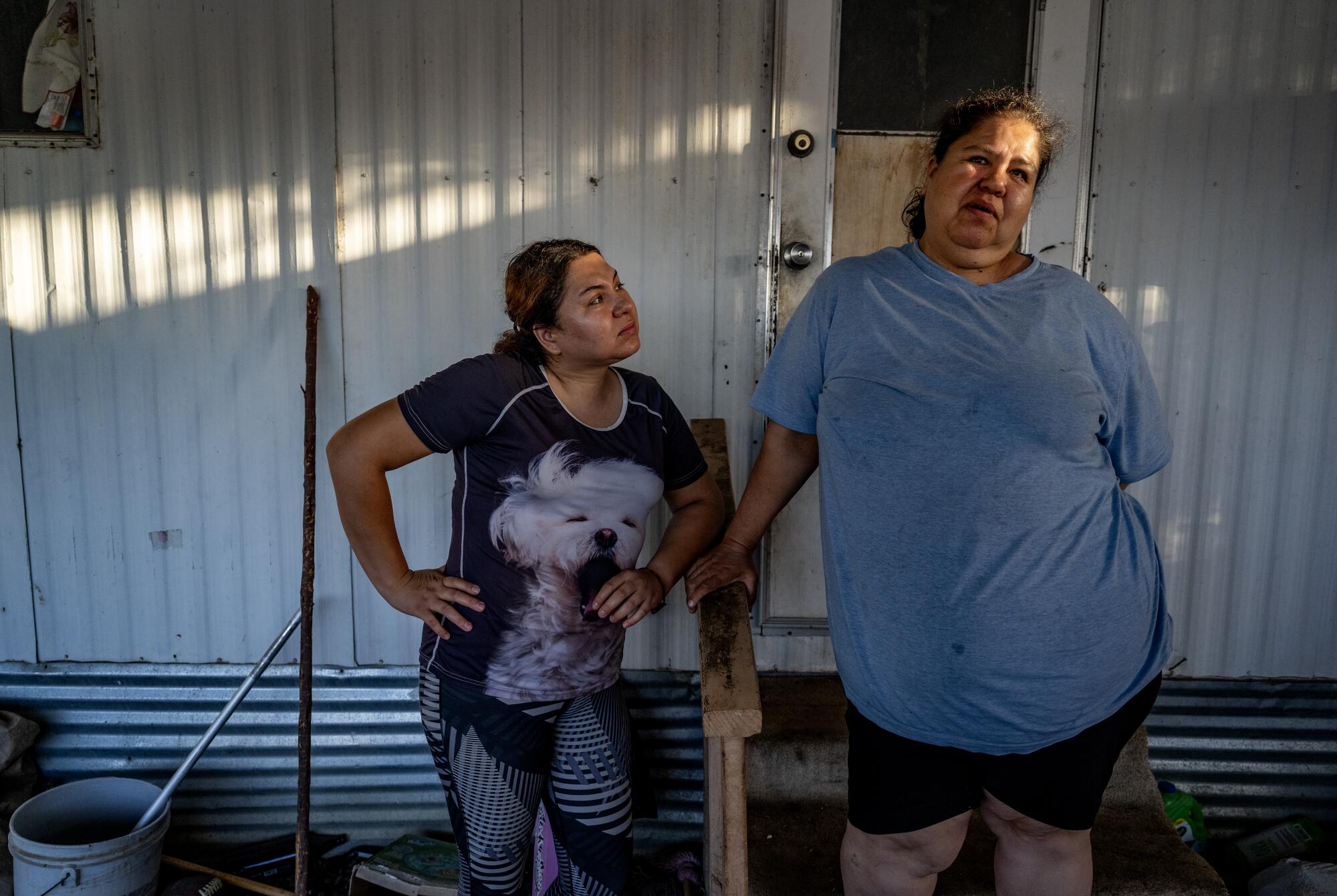 Two women stand in front of a mobile home. 