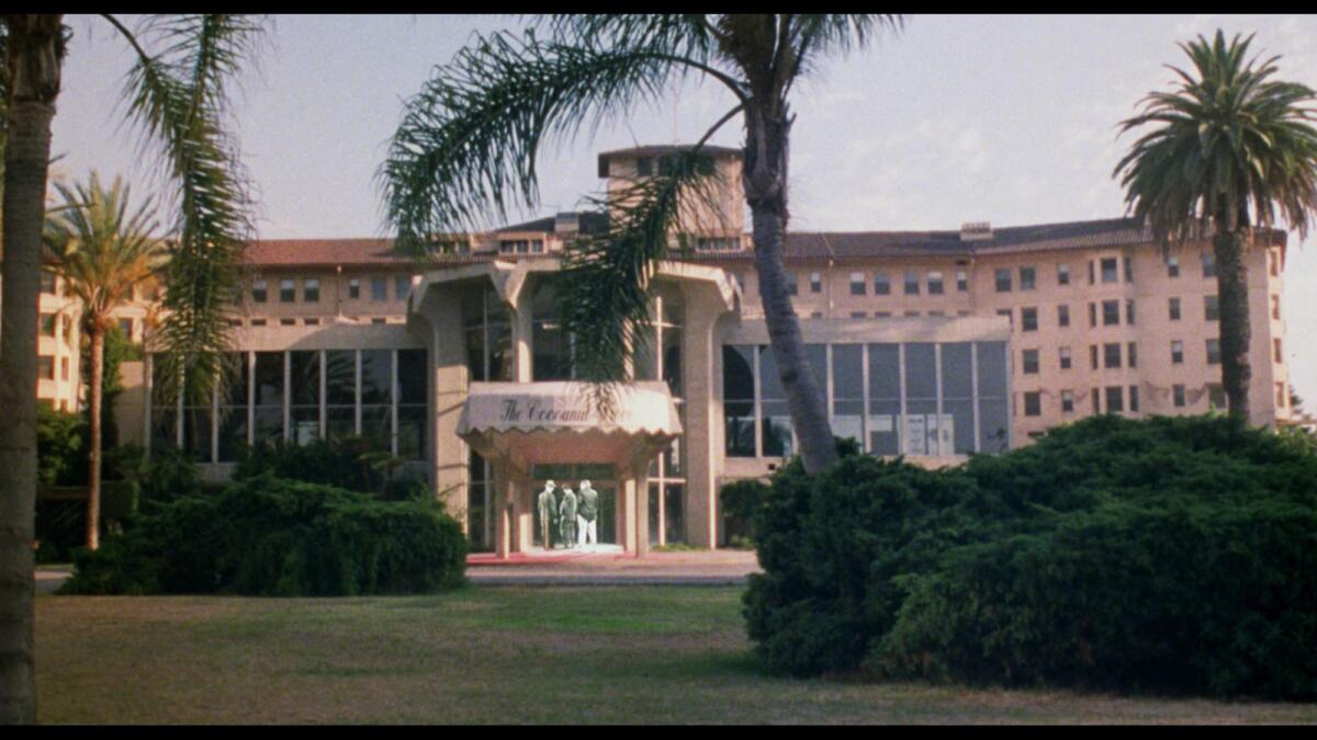 A film still shows the facade of the Ambassador Hotel with a group of ghostly figures gathered under the porte cochere.