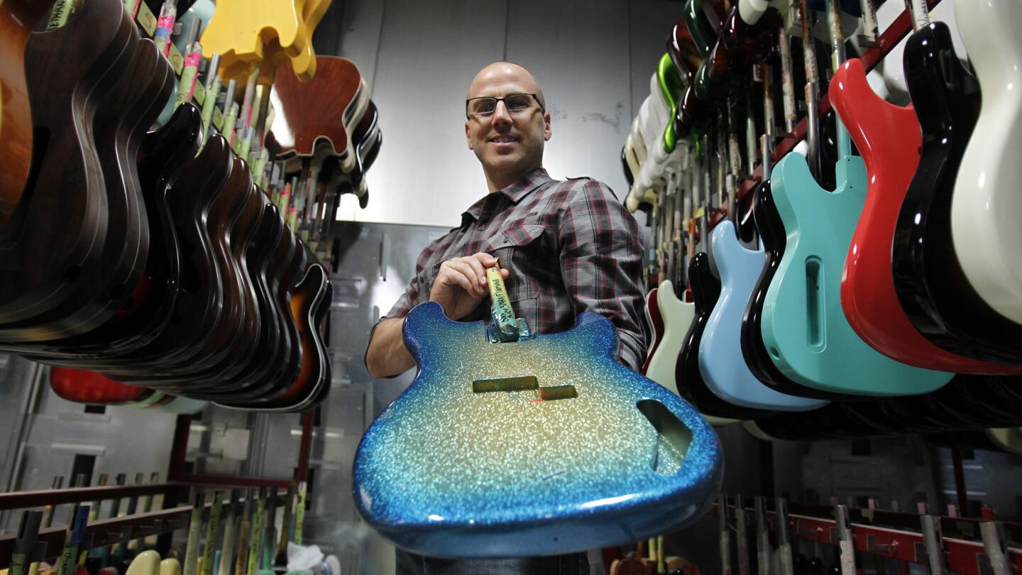 Justin Norvell, vice president of product marketing, shows off a custom built guitar at the Fender factory in Corona.