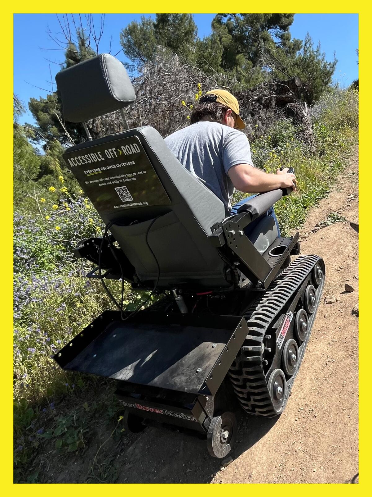 a man in an electric wheelchair climbing a hill on a hiking trail