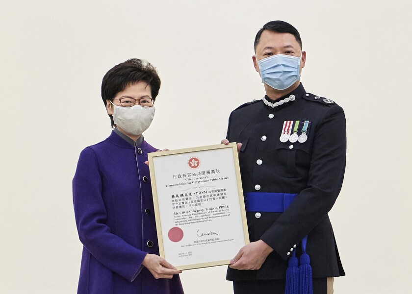 In this photo released by Hong Kong Government Information Services, Hong Kong Chief Executive Carrie Lam, left, presents the award to Hong Kong's Director of National Security Frederic Choi at Government House in recognition of his significant contributions to safeguarding national security in Hong Kong on Feb. 10, 2021. The top Hong Kong national security officer was reportedly caught up in a raid on an unlicensed massage business, and will face a police force investigation into the alleged misconduct. Choi has since been put on leave after the incident, according to Hong Kong police chief Chris Tang. (Hong Kong Government Information Services via AP)