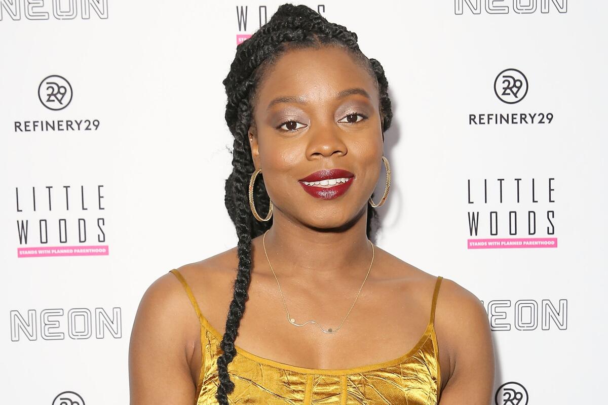 A woman with braided hair smiling in a gold dress