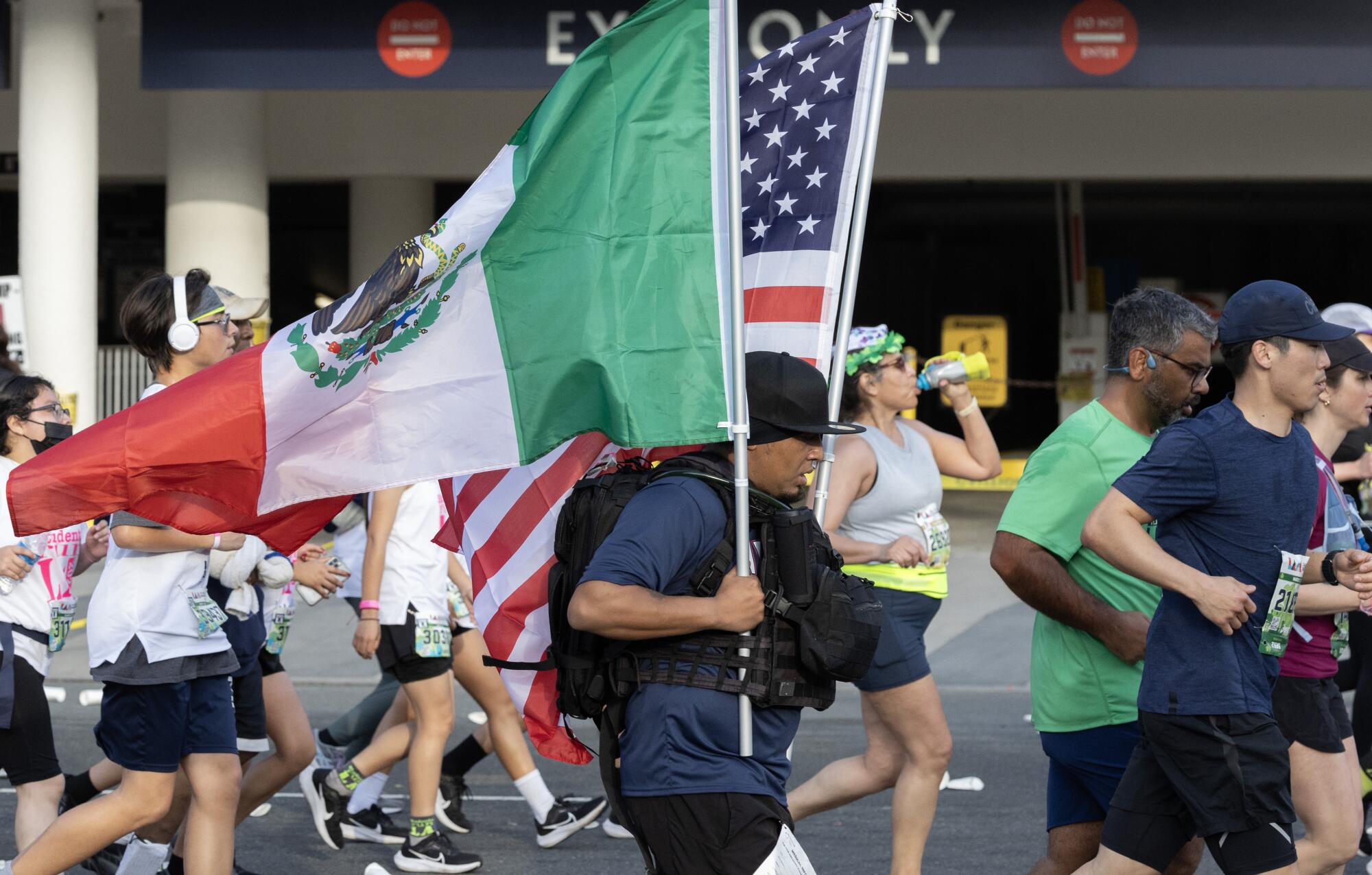 一名跑步者在洛杉矶马拉松比赛中举着美国和墨西哥国旗。