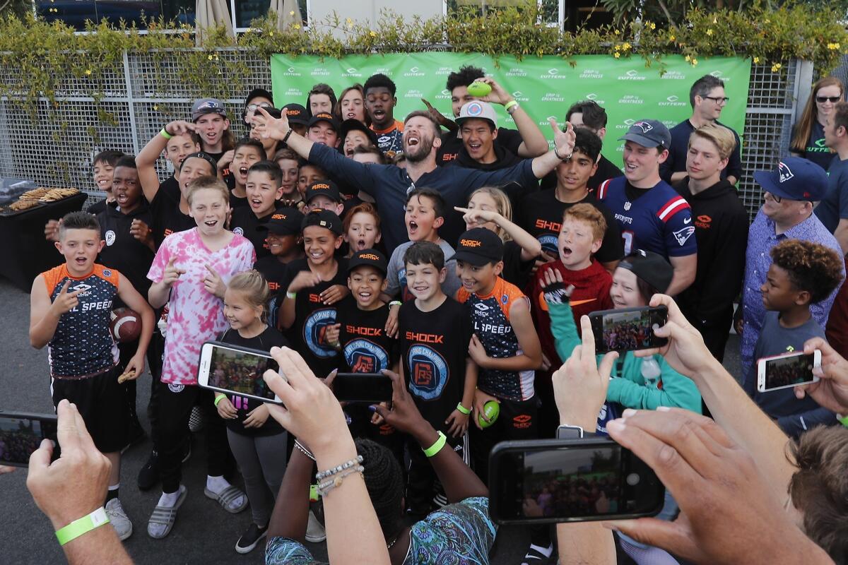 New England Patriots wide receiver Julian Edelman, top center, cheers during a group photo with youth athletes at United Sports Brands headquarters in Fountain Valley on Tuesday.