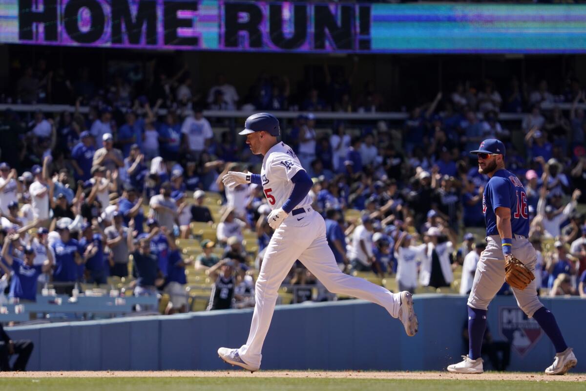 Los Angeles Dodgers' Freddie Freeman, left, rounds third after hitting a solo home run as Chicago Cubs third baseman Patrick Wisdom watches during the sixth inning of a baseball game Sunday, July 10, 2022, in Los Angeles. (AP Photo/Mark J. Terrill)