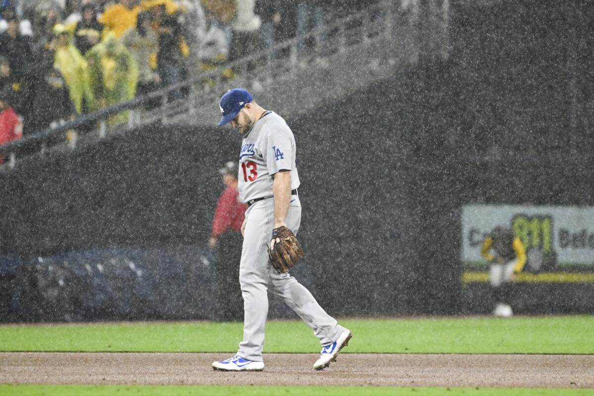 Dodgers second baseman Max Muncy walks on the field in the rain.