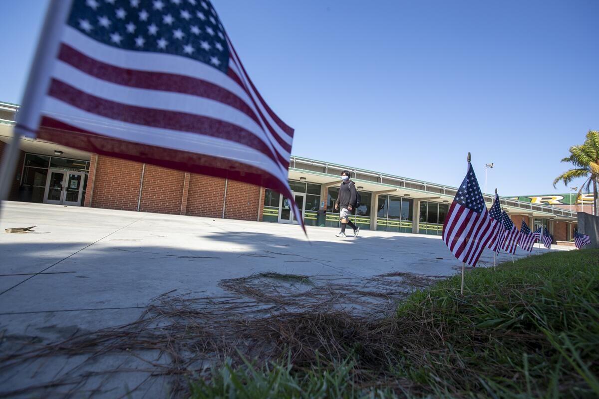 A student at Edison High School in Huntington Beach, walks past 500 American flags that are planted in the middle of campus.